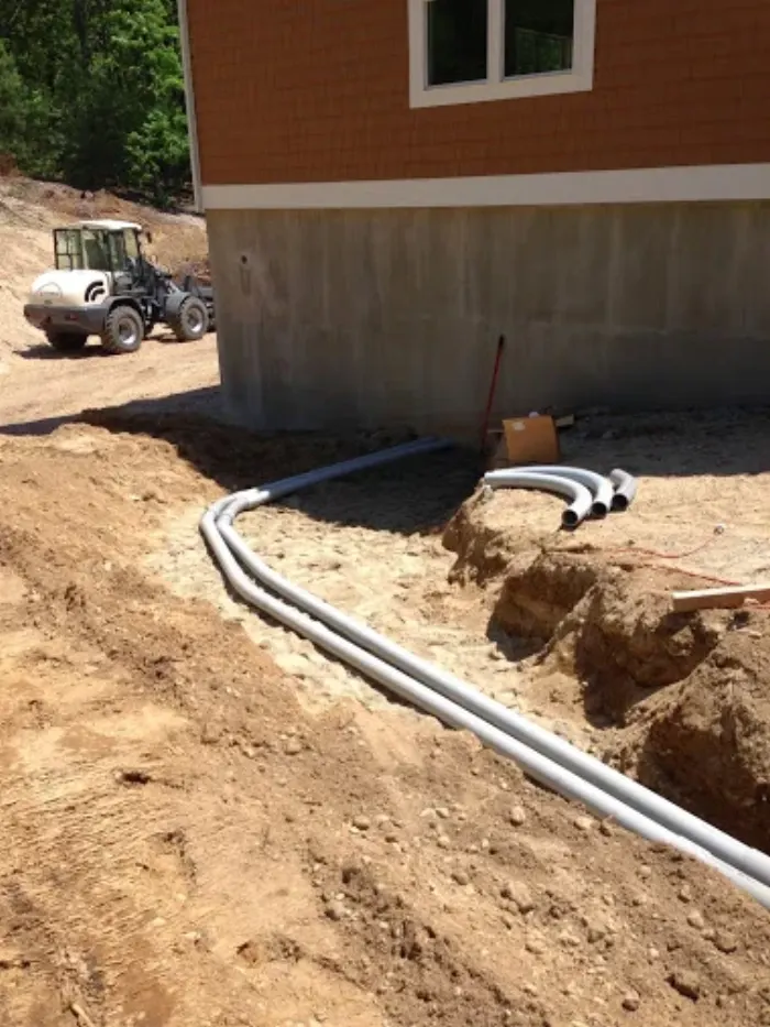 Conduit run buried in a trench beside a new foundation