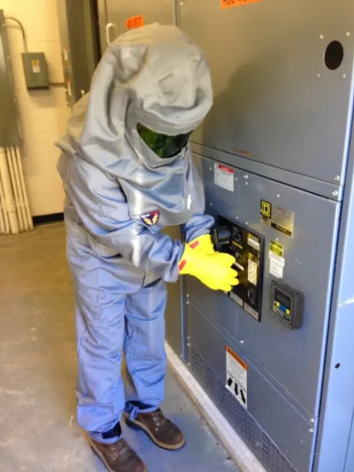 Electrician in an arc-flash suit working on switchgear