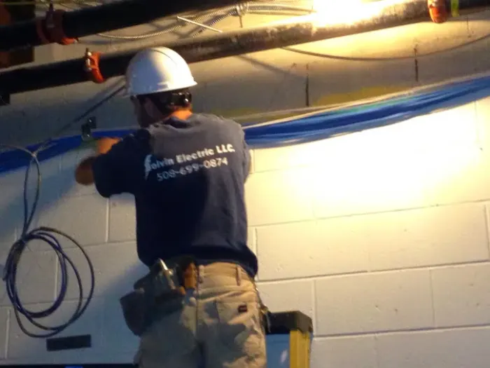 Electrician pulling cable along a ceiling in a hard hat