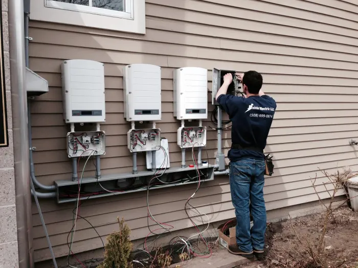 Electrician working on solar inverters mounted on a house