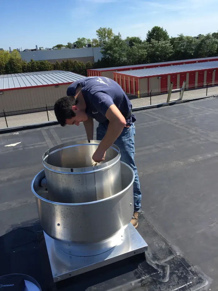 Electrician servicing a rooftop exhaust fan