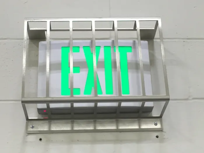 Illuminated green exit sign in a protective cage